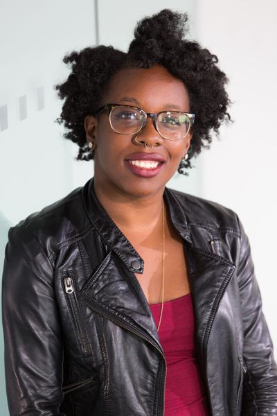 Michelle, a black woman with glasses, wearing a leather jacket.