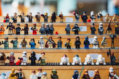 Many Lego figures on a shelf.