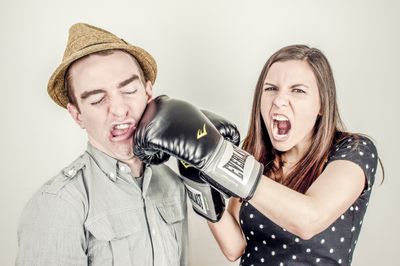 Woman punching man in face with boxing gloves.