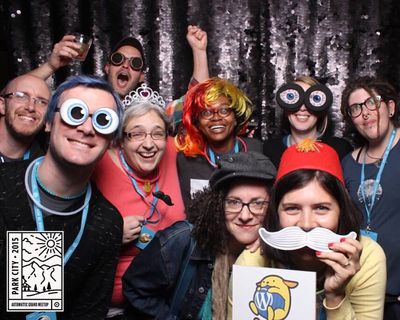 Several WordPress themers with holding crazy props and wearing wild hats in a photo booth but they're also smiling.