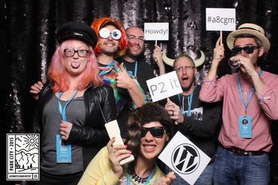 Several WordPress themers with holding crazy props and wearing wild hats in a photo booth.