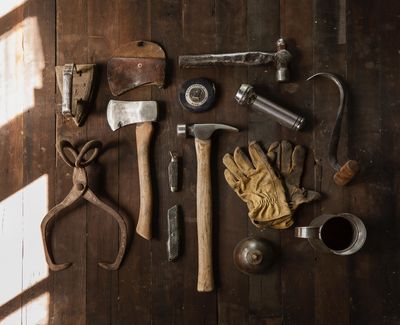 Clothes iron, hammer, axe, flashlight and pitcher on brown wooden table.