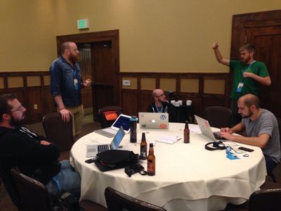 Four people sitting around a table with laptops, discussing technical stuff for a project.