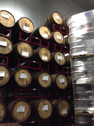 Barrels and kegs sitting next to each other inside a brewery.