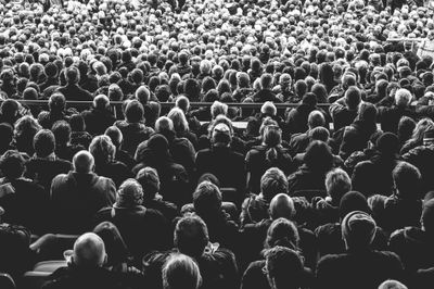 A grayscale photo of many people sitting in chairs.