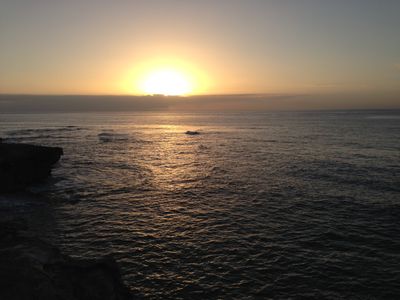 The Hawaiian shoreline near Lihue with the sun shining over a cloud during sunrise.