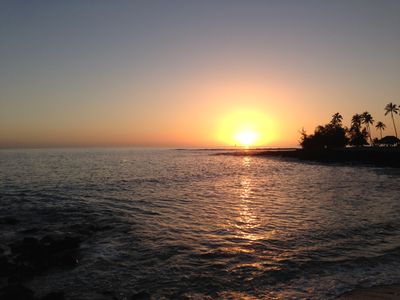 The Hawaiian shoreline near Lihue with the sun almost fully over the horizon during sunrise.