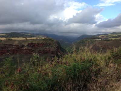 A random overlook with a canyon view near Lihue, complete with grass, mountains and a steep drop off.