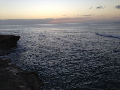 The Hawaiian shoreline at sunrise near Lihue, with a few rocks jetting out into a sunlit ocean.