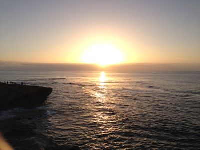 The Hawaiian shoreline near Lihue with the sun shining halfway over a cloud during sunrise.