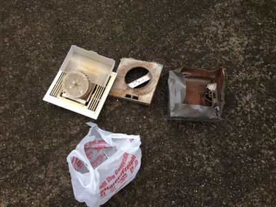 An old bathroom fan, broken in pieces and bent up.