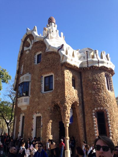A building in Parc Güell, a park in Barcelona, Spain. It has a white, stone roof and sandy colored stones.