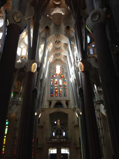 A stained glass window of orange high toward the ceiling in La Sagrada Familia, an ornate church in Barcelona, Spain.