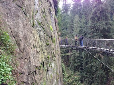 A view of people walking across the Cliff Walk in Capilano Suspension Bridge Park, which is next to a giant, steep cliff.