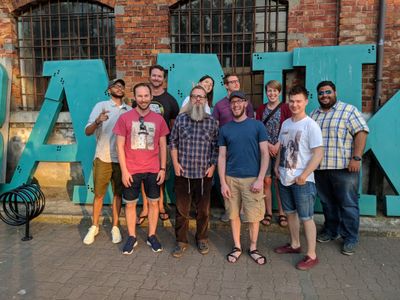 Ten people in a team photo in front of a blue Bank sign, smiling and making silly faces.