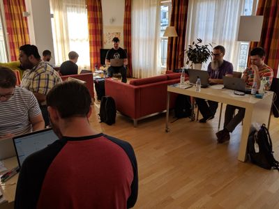 Several people sitting at tables and couches working on computers.