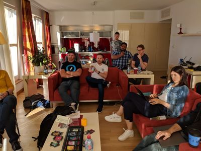 Several people sitting at tables and couches looking at a TV.
