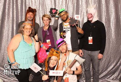 Many people/themers posting in a photo both, holding signs, silly props and wearing funny masks and faces.