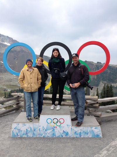 People standing on a podiums, like at the Olympics, with the rings in the background.