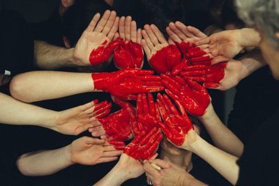 Hands formed together with red heart paint.